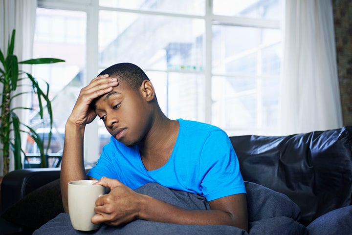 young man sitting on sofa looking sick and tired