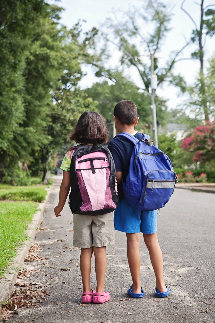 Two grade school age children walking to school or school bus stop.