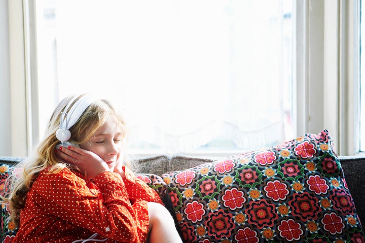 young girl listening to music on sofa