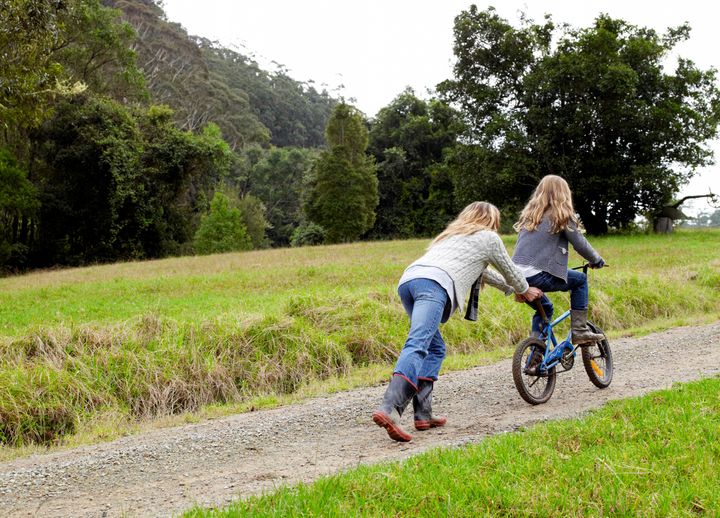 Mother pushing daughter up hill on her bicycle