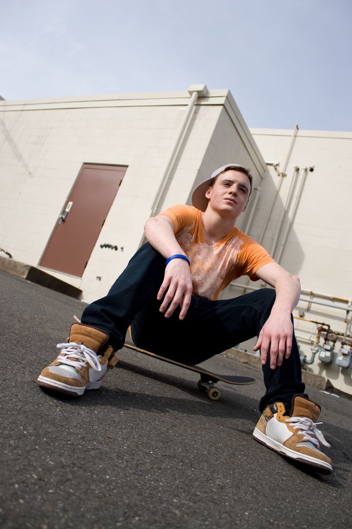A young skater resting on his skateboard.