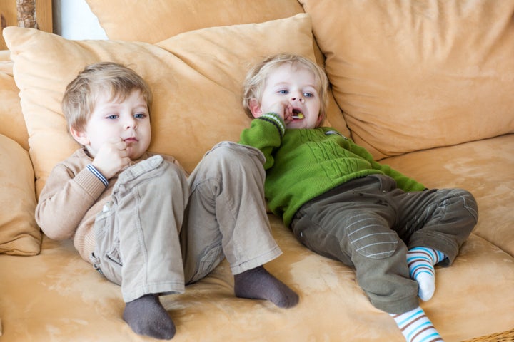 Two little brother boys watching tv and eating candy indoor