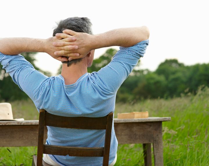 Man sitting at desk in countryside meadow.