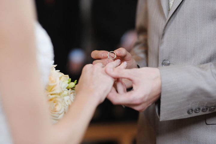 Groom putting a wedding ring on bride's finger