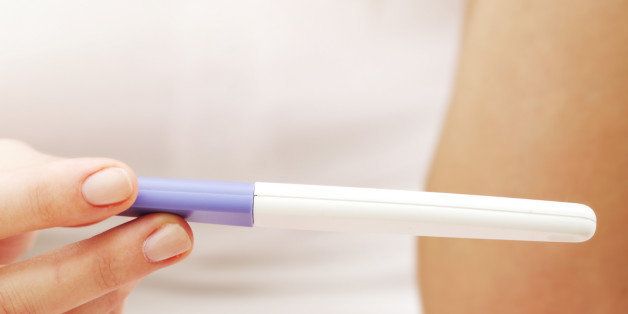 Smiling woman holding a pregnancy test.