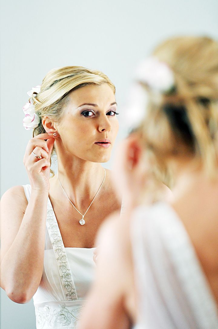 Beautiful bride with wedding gown looking through mirror