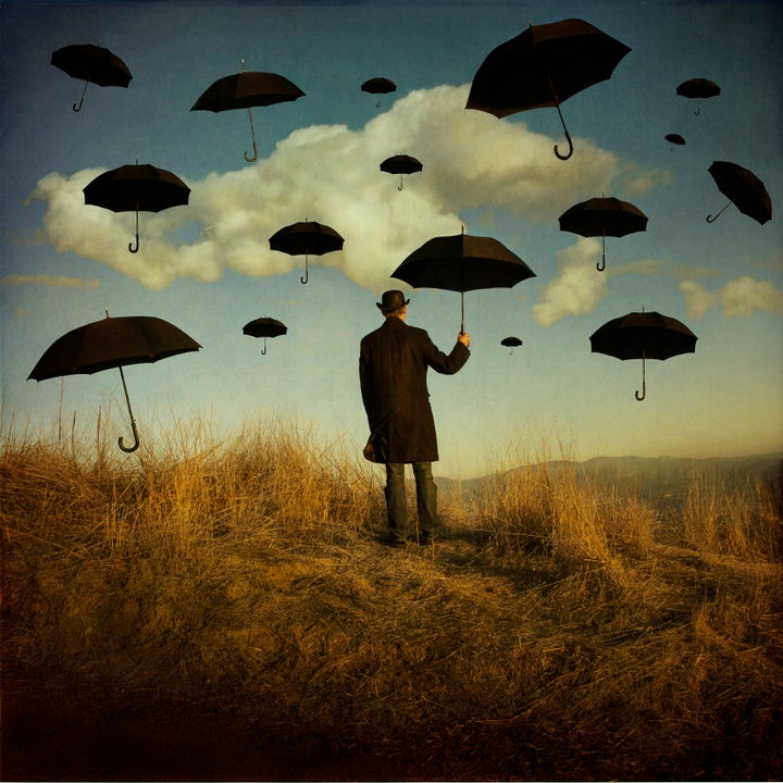 Man holding umbrella against sky.