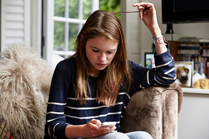 Teenage looking at cellphone and playing with her hair