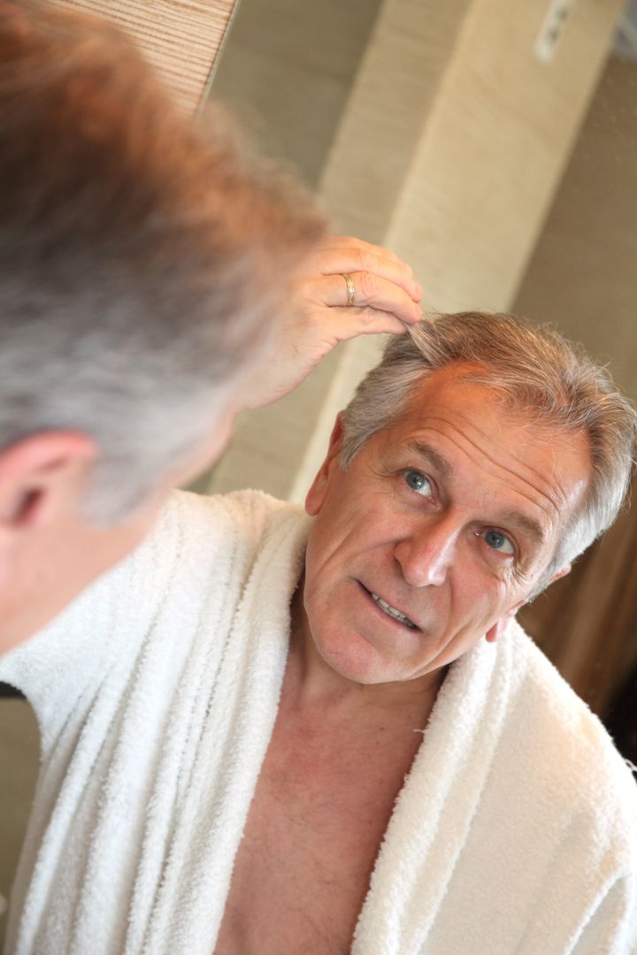 Senior man looking at hair in mirror