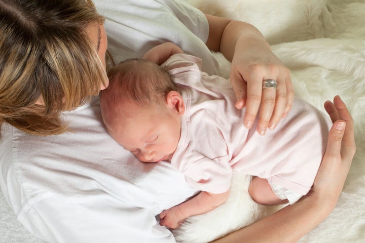 Young loving mother watching her sleeping 18 days old baby