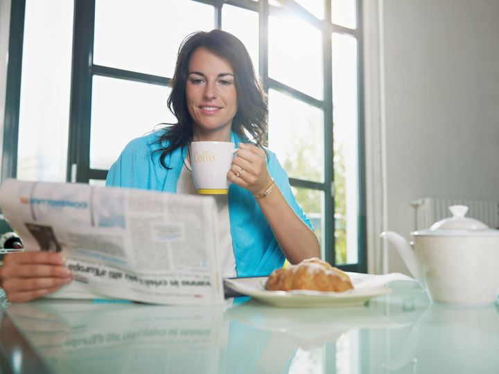 mid adult woman drinking coffee and reading news. Horizontal shape, copy space