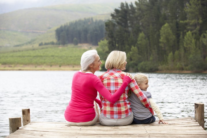 Mother, daughter and grandmother sitting on a jetty