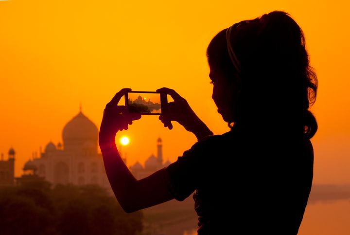 Girl photographing the Taj Mahal with a smartphone