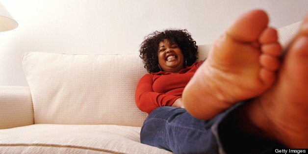 Woman sitting on couch laughing, feet on coffee table