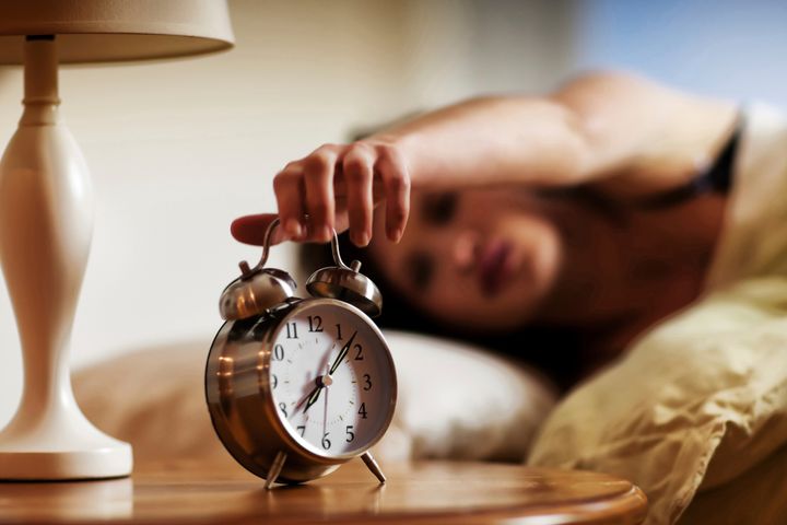 Woman Turning Off The Alarm Clock In The Morning