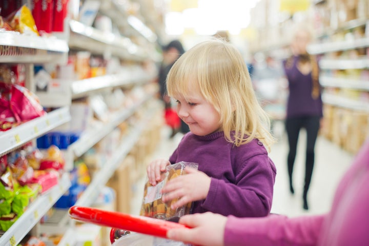 Mother and daughter in bakery section of supermarket. Daughter with cookies