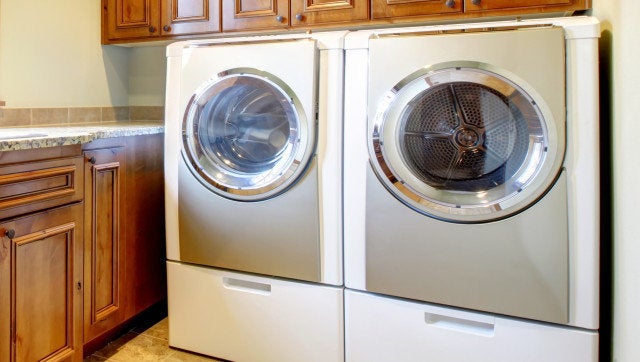 Luxury laundry room with wood cabinets and tile floor.