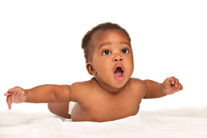 3-month old African American baby boy lay on the bed with arms out