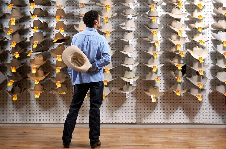 Man looking at cowboy hats in store, rear view