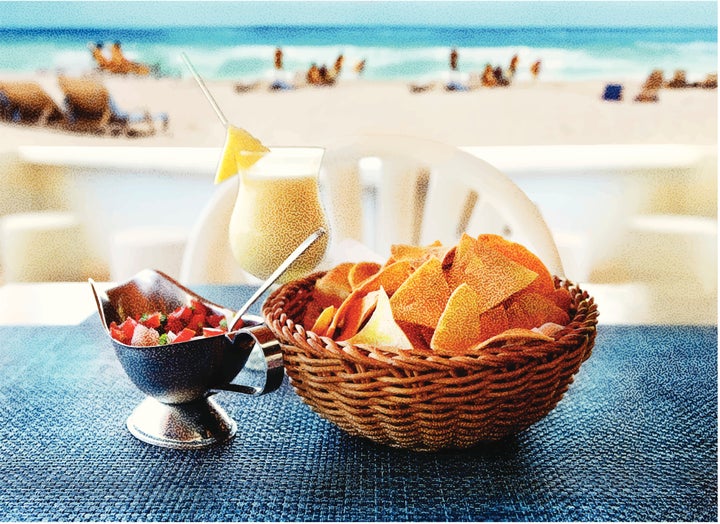 Stipple engraving of tortilla chips with salsa and a pina colada at a luxury tropical resort.