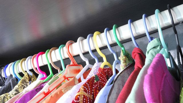 Rows of colorful clothes hanger in wardrobe.
