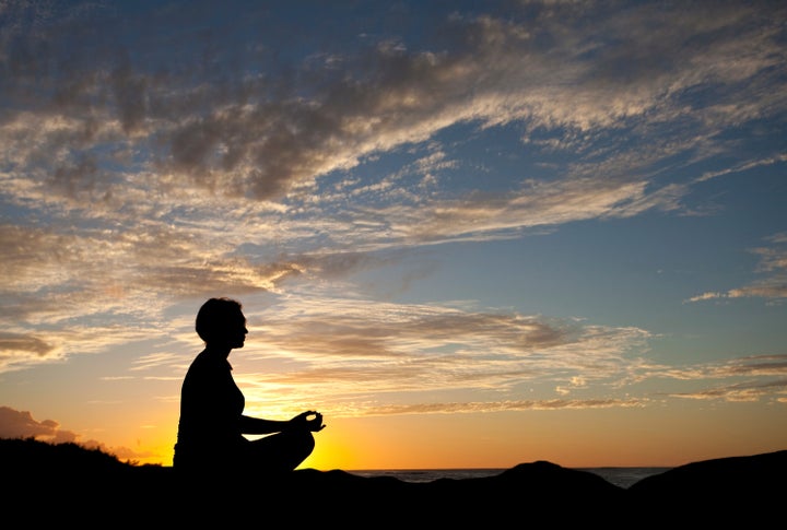 A silhouette of a woman doing yoga on a beach in the tropics. Hawaii, United States. Sunset. Colour image. Horizontal.