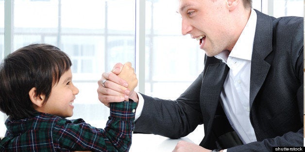 Young father and son wrestling with arms, competition fight parenting concept indoor