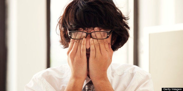 man rubbing his eyes at work