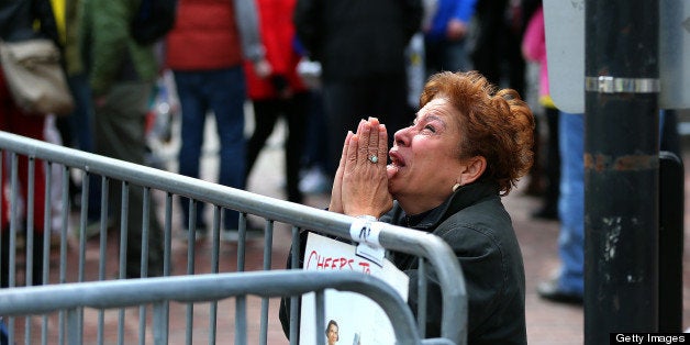 BOSTON - APRIL 15: A woman kneels and prays at the scene of the first explosion on Boylston Street near the finish line of the 117th Boston Marathon on April 15, 2013. (Photo by John Tlumacki/The Boston Globe via Getty Images)