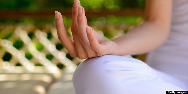 A female yoga instructor is sitting outside with lotus position