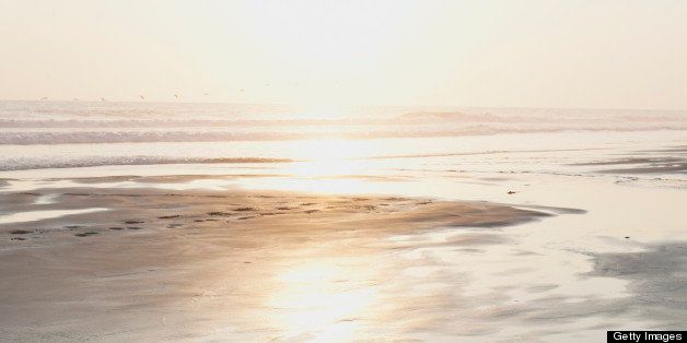 Girl meditating on an empty beach at sunset