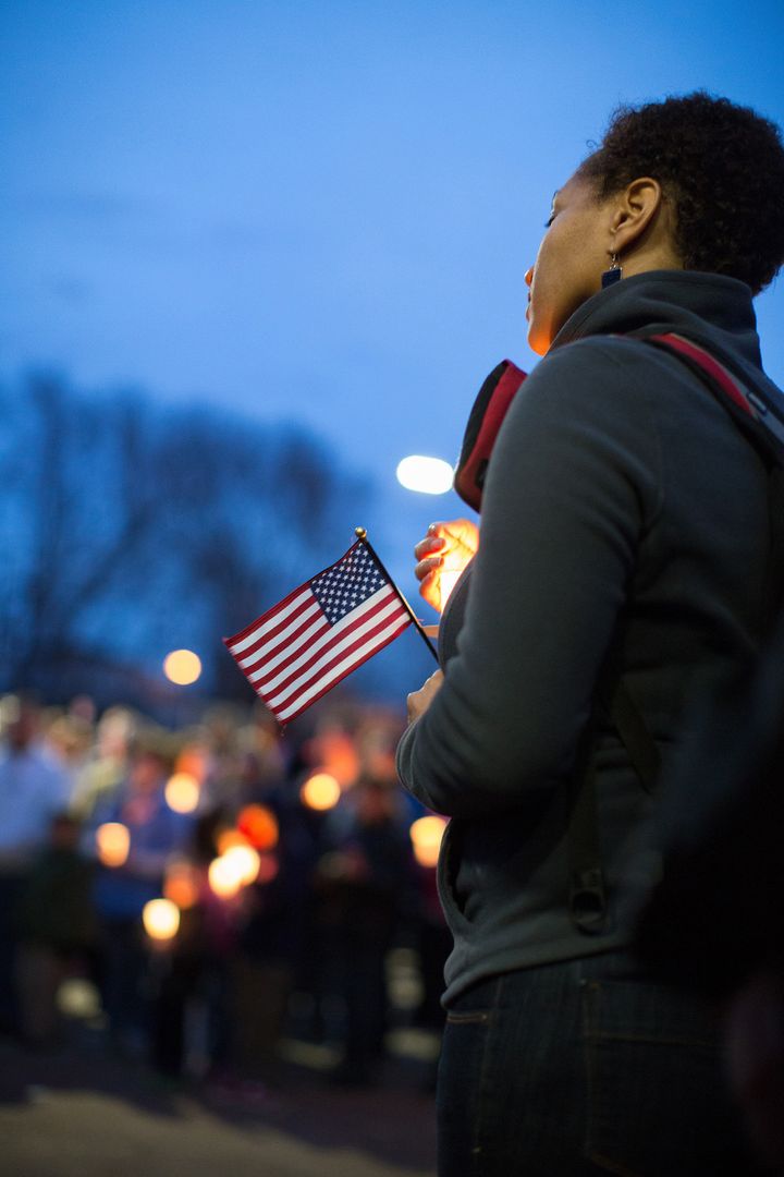 A mourner holds a candle and a U.S. flag during a vigil for Martin Richard, one of three killed in the Boston Marathon bombings, at Garvey Park in Boston, Massachusetts, U.S., on Tuesday, April 16, 2013. Richard, an 8-year-old from Boston's Dorchster neighborhood, was among the dead in blasts that also injured his mother and sister. Photographer: Scott Eisen/Bloomberg via Getty Images