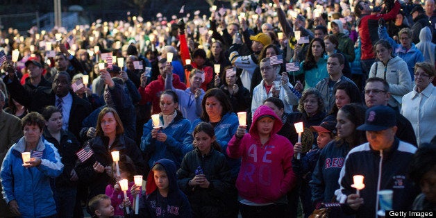 Mourners hold candles and U.S. flags during a vigil for Martin Richard, one of three killed in the Boston Marathon bombings, at Garvey Park in Boston, Massachusetts, U.S., on Tuesday, April 16, 2013. Richard, an 8-year-old from Boston's Dorchster neighborhood, was among the dead in blasts that also injured his mother and sister. Photographer: Scott Eisen/Bloomberg via Getty Images