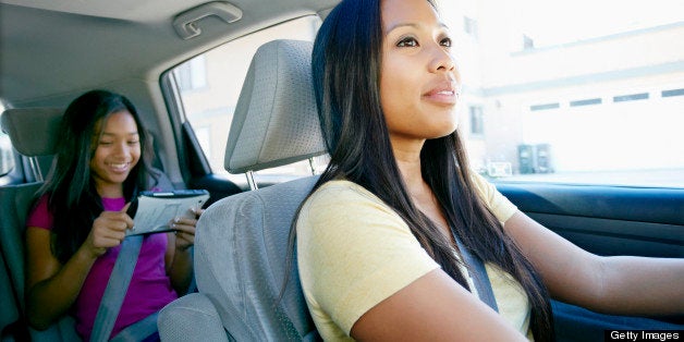 Mother watching daughter use technology in car