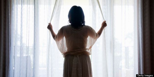 a woman opening curtains of hotel room