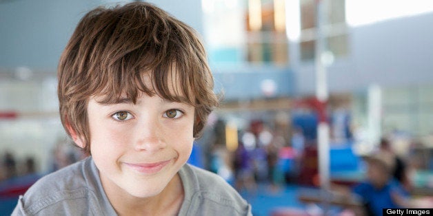 8-9 year old kid smiling while climbing around in a gym, portrait