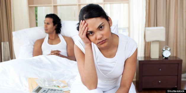 Upset couple sitting on the bed separately after an argument