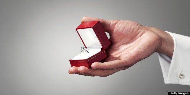 Man holding engagement ring, close-up of hand