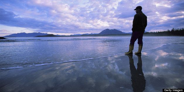 Vargas Island, Clayoquot Sound, Vancouver Island, British Columbia, Canada. A man stands at the tide-line on Vargas Island at dawn.