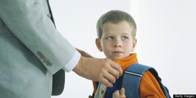 Man buttoning coat of boy with backpack