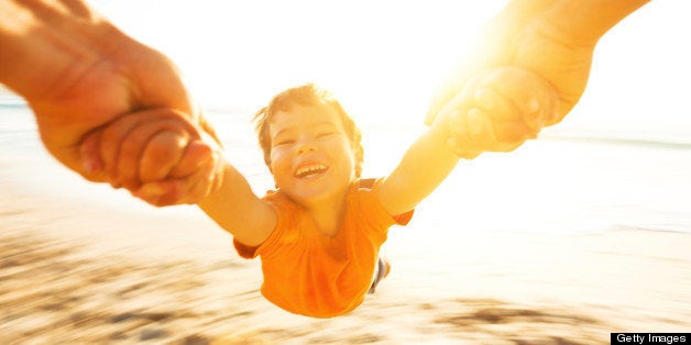 Happy boy spinning around his father on a beach. Motion blur.