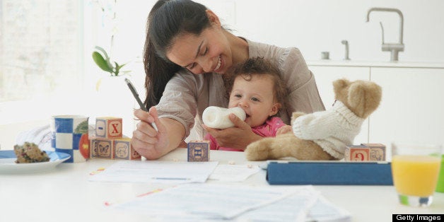 Hispanic woman working and holding baby daughter