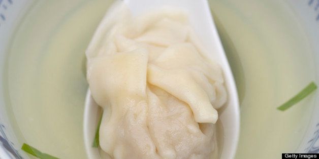 Close up of dumpling on spoon in won ton soup