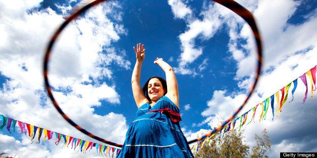 Pregnant woman hula hooping at festival.