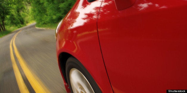 red car driving through a green ...