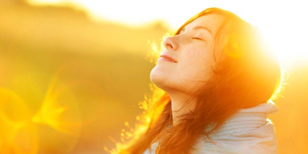 Young woman enjoying sunlight. Natural sun and optical flare. The concept of freedom and healthy lifestyle