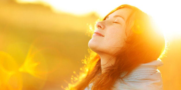 Young woman enjoying sunlight. Natural sun and optical flare. The concept of freedom and healthy lifestyle