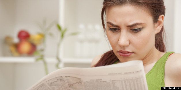 young woman reading bad news in newspaper at home