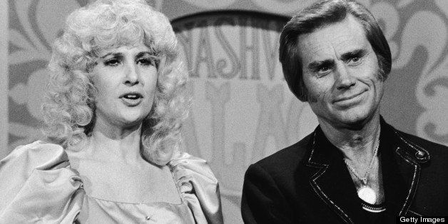 American country and western musicians Tammy Wynette and George Jones in a publicity still on the set of the television program 'Nashville Palace,' 1981. Ms. Wynette wears a ruffled, puffy dress and wig while Mr. Jones wears a scoop necked t-shirt and gold medallion under an embroidered jacket. (Photo by Frank Driggs Collection/Getty Images)