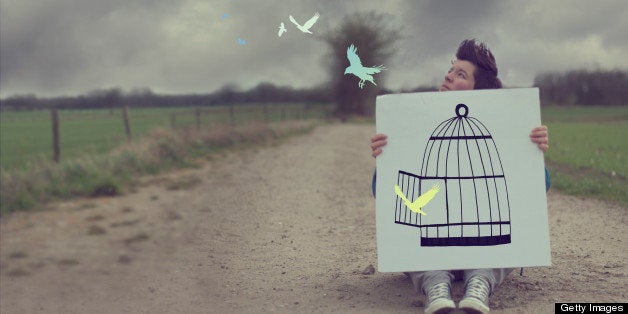 Woman with drawing of cage with pastel colored flying birds.